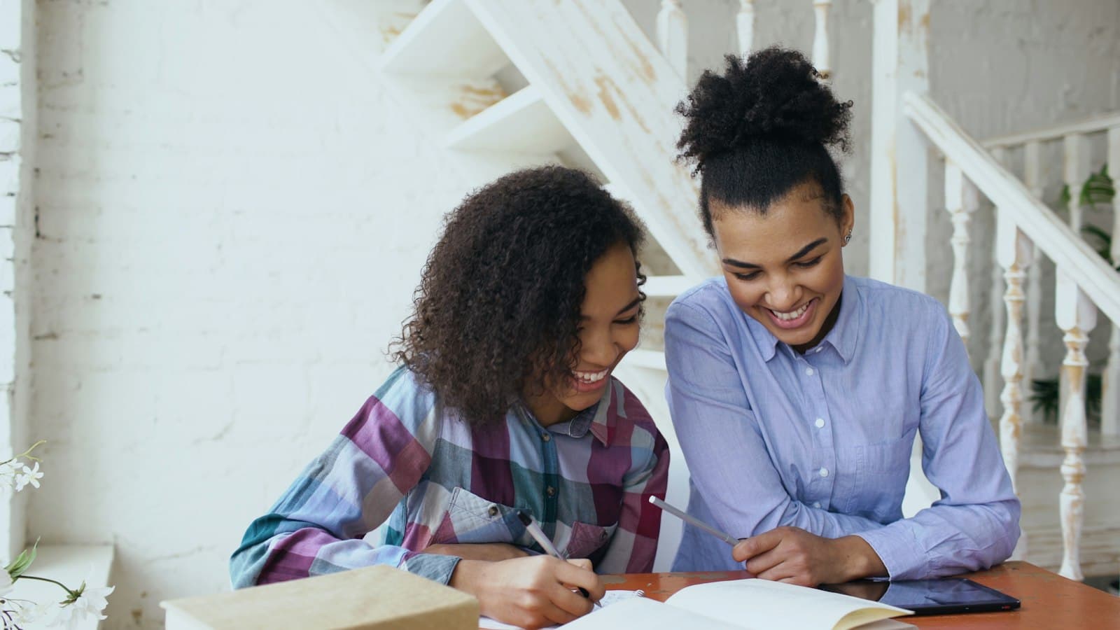 Two students laughing as they work through a notebook together
